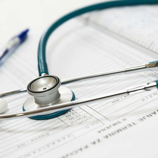 A stethoscope and pen resting on a medical report in a healthcare setting.